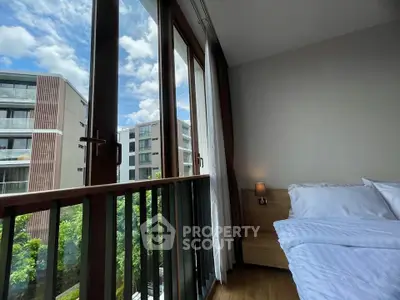 Modern bedroom with large windows offering a stunning view of contemporary buildings and lush greenery.