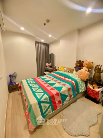 Cozy bedroom with colorful bedding and plush toys, perfect for a comfortable living space.
