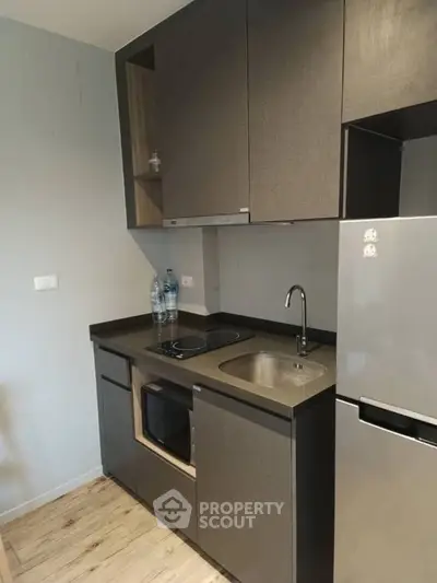 Modern compact kitchen with sleek cabinetry and built-in appliances in a stylish apartment.