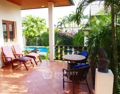 Charming patio with pool view and lush greenery, perfect for relaxation.