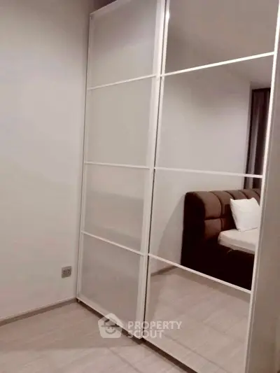 Modern bedroom with mirrored sliding wardrobe and cozy bed.