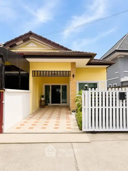 Charming yellow house with tiled roof and gated driveway in a serene neighborhood.