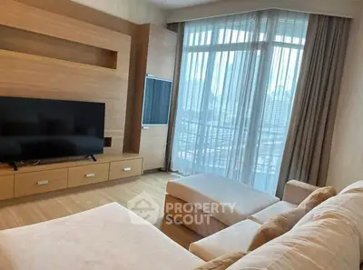 Spacious living room with modern TV setup and large windows offering city views.