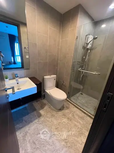 Modern bathroom with glass shower and sleek fixtures in contemporary apartment.