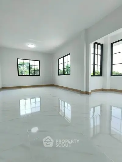 Spacious and bright living room with large windows and glossy floor tiles.