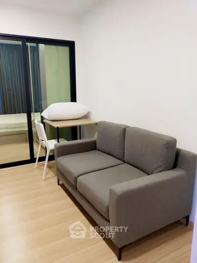Modern living room with sleek gray sofa and wooden flooring, perfect for cozy urban living.