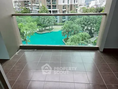 Spacious balcony with stunning pool view in modern apartment complex.
