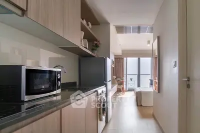 Modern kitchen with sleek appliances and open layout leading to a bright living area with balcony view.