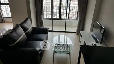Modern living room with sleek black sofa and glass table, city view from balcony.