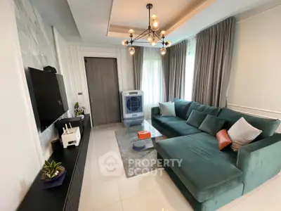 Modern living room with stylish chandelier and plush green sectional sofa