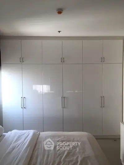 Spacious bedroom with large built-in white wardrobe and cozy bed.