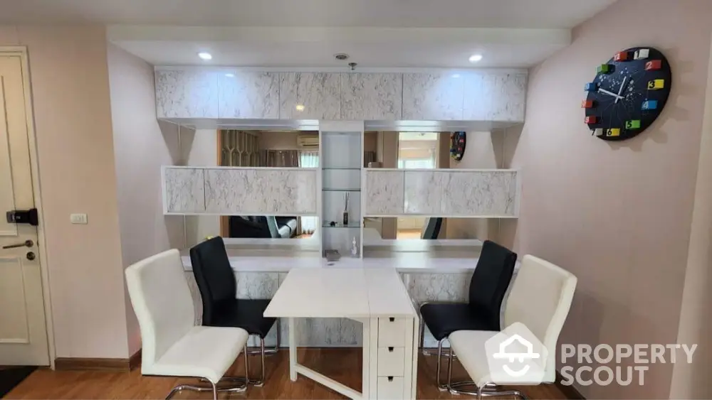 Modern dining area with stylish chairs and wall-mounted clock in a cozy apartment