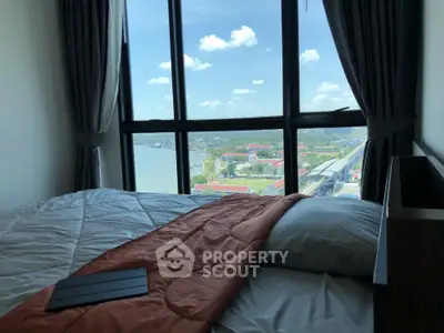 Spacious bedroom with large windows offering a panoramic view of the cityscape and waterfront, bathed in natural light.
