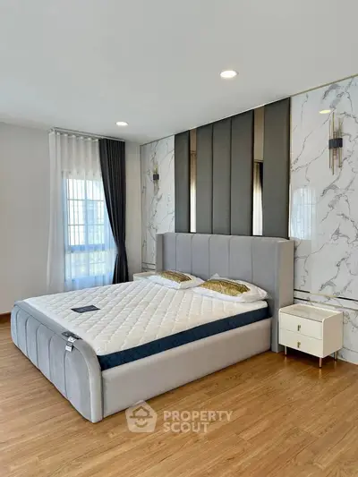 Luxurious bedroom with elegant decor and large window, featuring a plush bed and stylish nightstand.