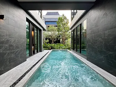 Luxurious modern home with sleek private pool and lush garden view.