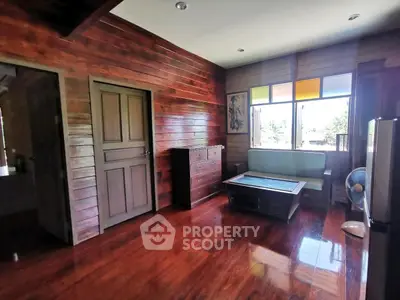 Charming wooden interior living room with polished floors and colorful window accents.