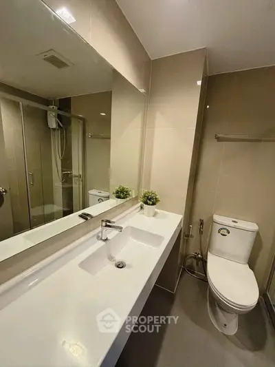 Modern bathroom with sleek fixtures and spacious shower in contemporary apartment.