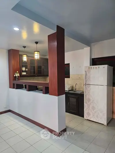 Spacious kitchen with modern lighting and large fridge in open layout design.