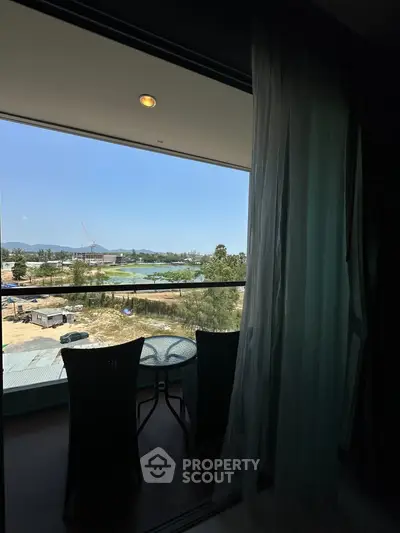 Spacious balcony with stunning view overlooking construction site and greenery.