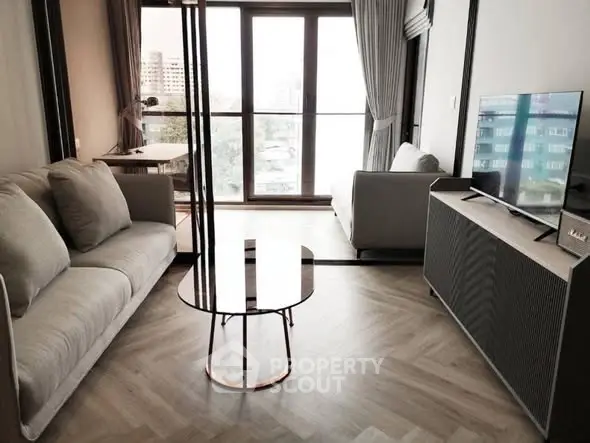 Modern living room with stylish furniture and large windows offering city views.