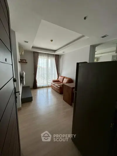 Cozy living room with leather sofa and large window, perfect for relaxation.