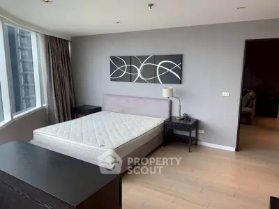 Spacious modern bedroom with large windows and stylish decor in a high-rise apartment.