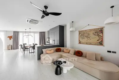 Modern open-plan living room with stylish furniture and dining area, featuring a sleek kitchen design.