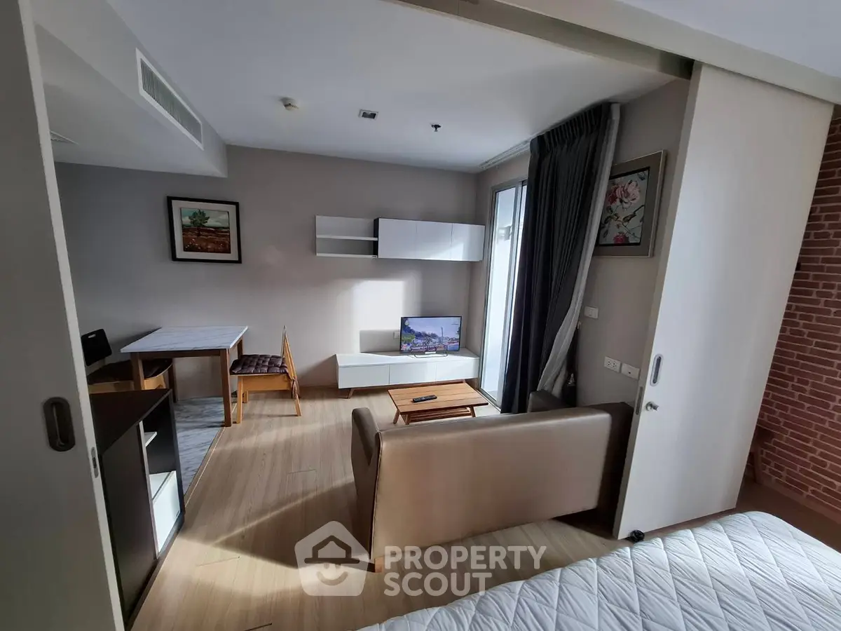 Modern living room with stylish decor and natural light, featuring a cozy seating area and a small dining table.