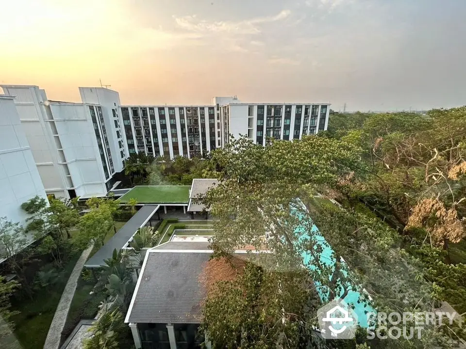 Stunning aerial view of modern apartment complex with lush greenery and inviting pool area.