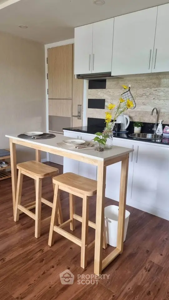 Modern kitchen with wooden bar stools and sleek cabinetry, perfect for cozy dining and efficient cooking.
