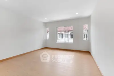Spacious empty room with large windows and wooden flooring, perfect for customization.