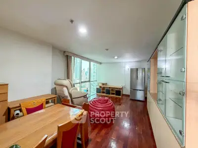 Spacious living room with wooden flooring and city view, featuring modern furniture and ample natural light.