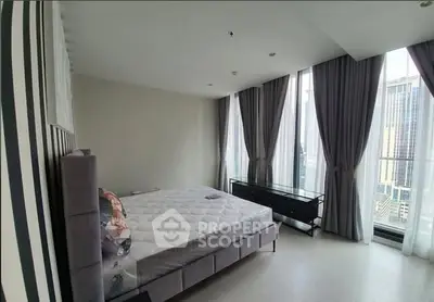 Spacious bedroom with floor-to-ceiling windows and city view