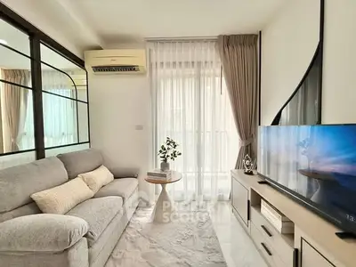 Bright modern living room with cozy sofa and large TV, featuring elegant decor and natural light.