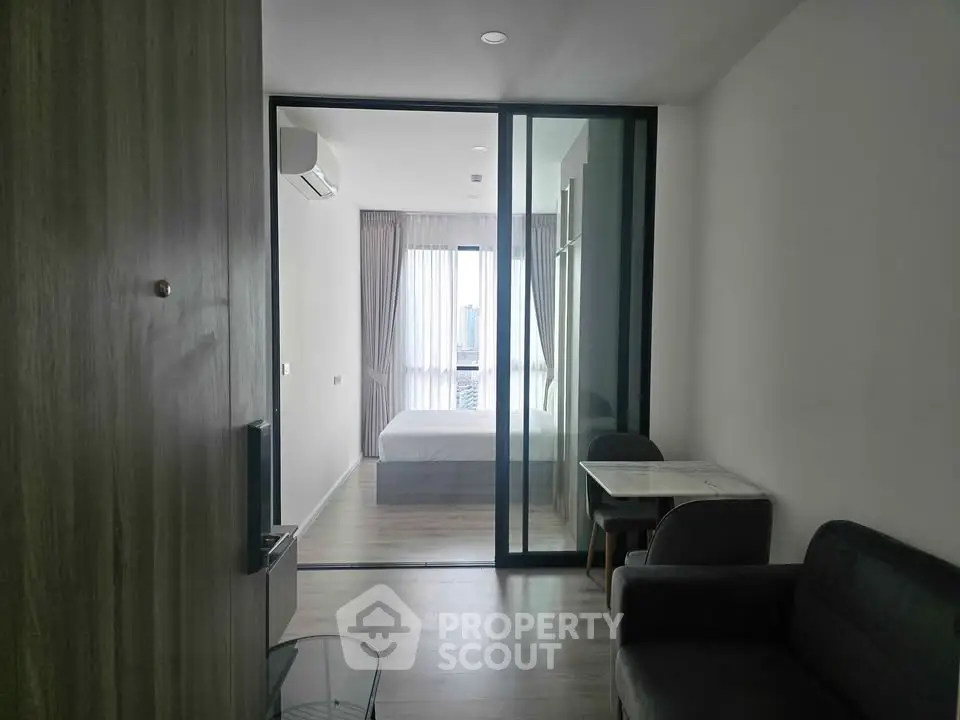 Modern apartment interior with glass partition, cozy living area, and bright bedroom.