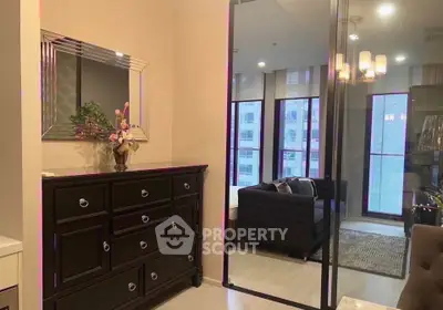 Stylish bedroom with elegant dresser and large mirror reflecting cozy living area.