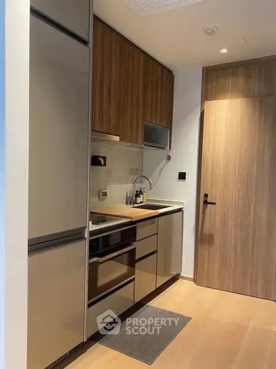 Modern compact kitchen with sleek cabinetry and integrated appliances in a stylish apartment.