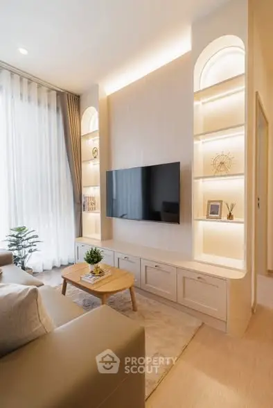 Modern living room with elegant built-in shelves and large TV, featuring cozy seating and natural light.