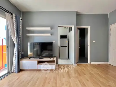 Modern living room with TV, shelves, and balcony access in stylish apartment.