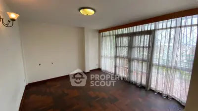Spacious living room with parquet flooring and large windows offering natural light.