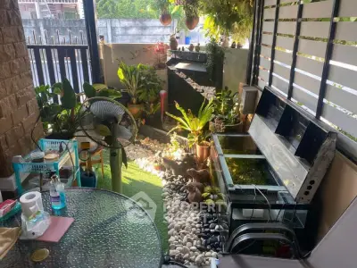 Charming balcony with lush greenery and cozy seating area, perfect for relaxation.