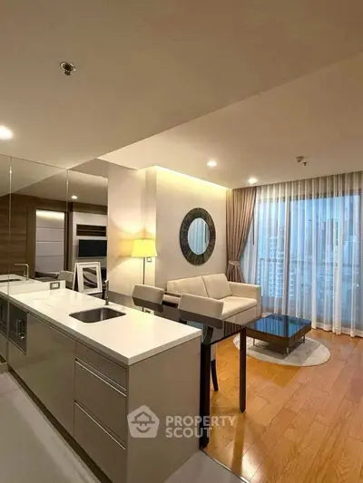 Modern open-layout living room with kitchen, featuring elegant decor and city view.
