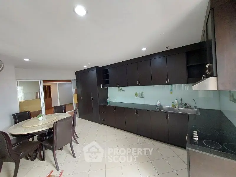 Spacious kitchen with dark wood cabinets and dining area in modern apartment