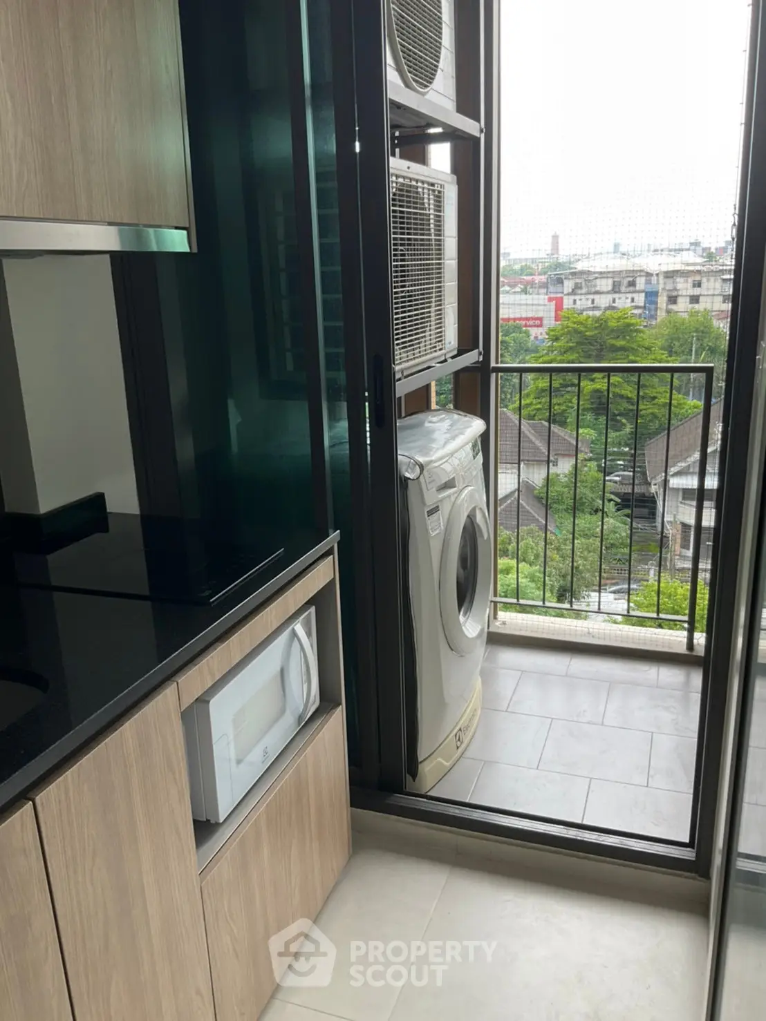 Modern kitchen with balcony view featuring washing machine and microwave