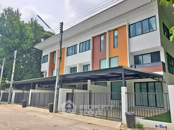 Modern townhouse exterior with sleek design and gated parking area, ideal for urban living.