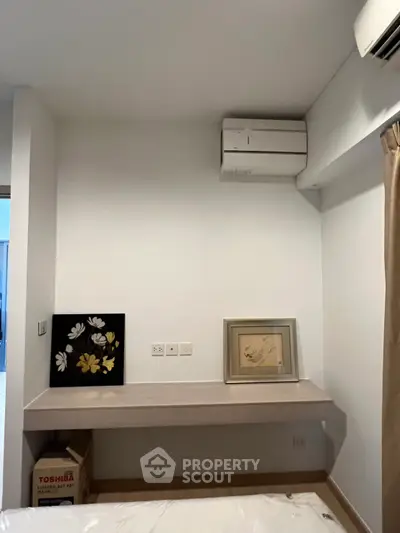 Modern bedroom with minimalist decor and air conditioning unit, featuring a sleek wall-mounted desk.