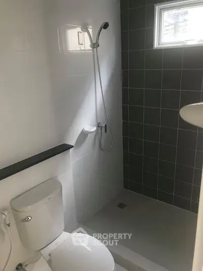 Modern bathroom with sleek shower and toilet in a minimalist design.