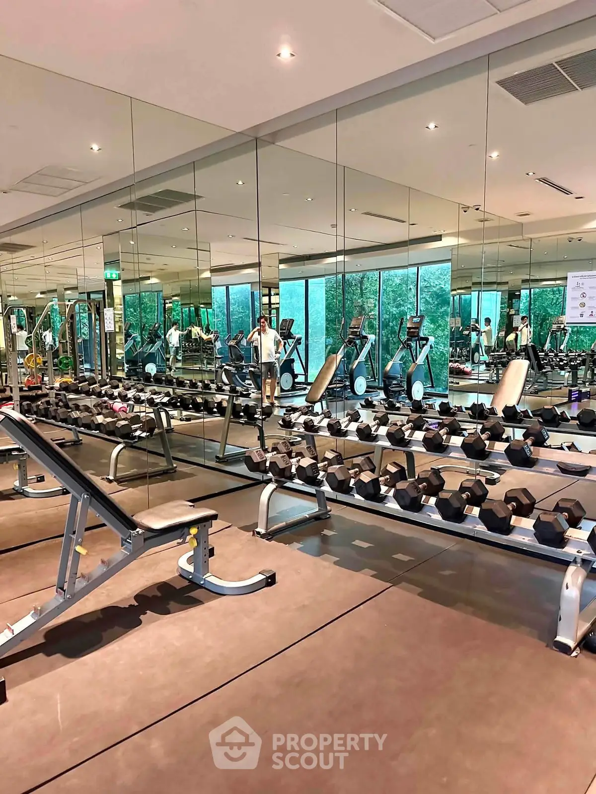 Spacious modern gym with mirrored walls and state-of-the-art equipment in luxury residential building.