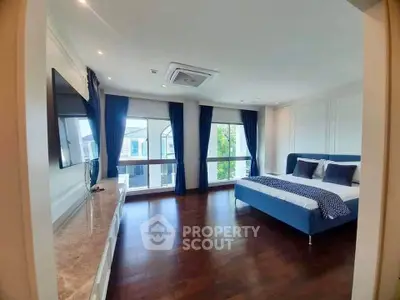 Spacious bedroom with large windows and elegant decor in modern home.