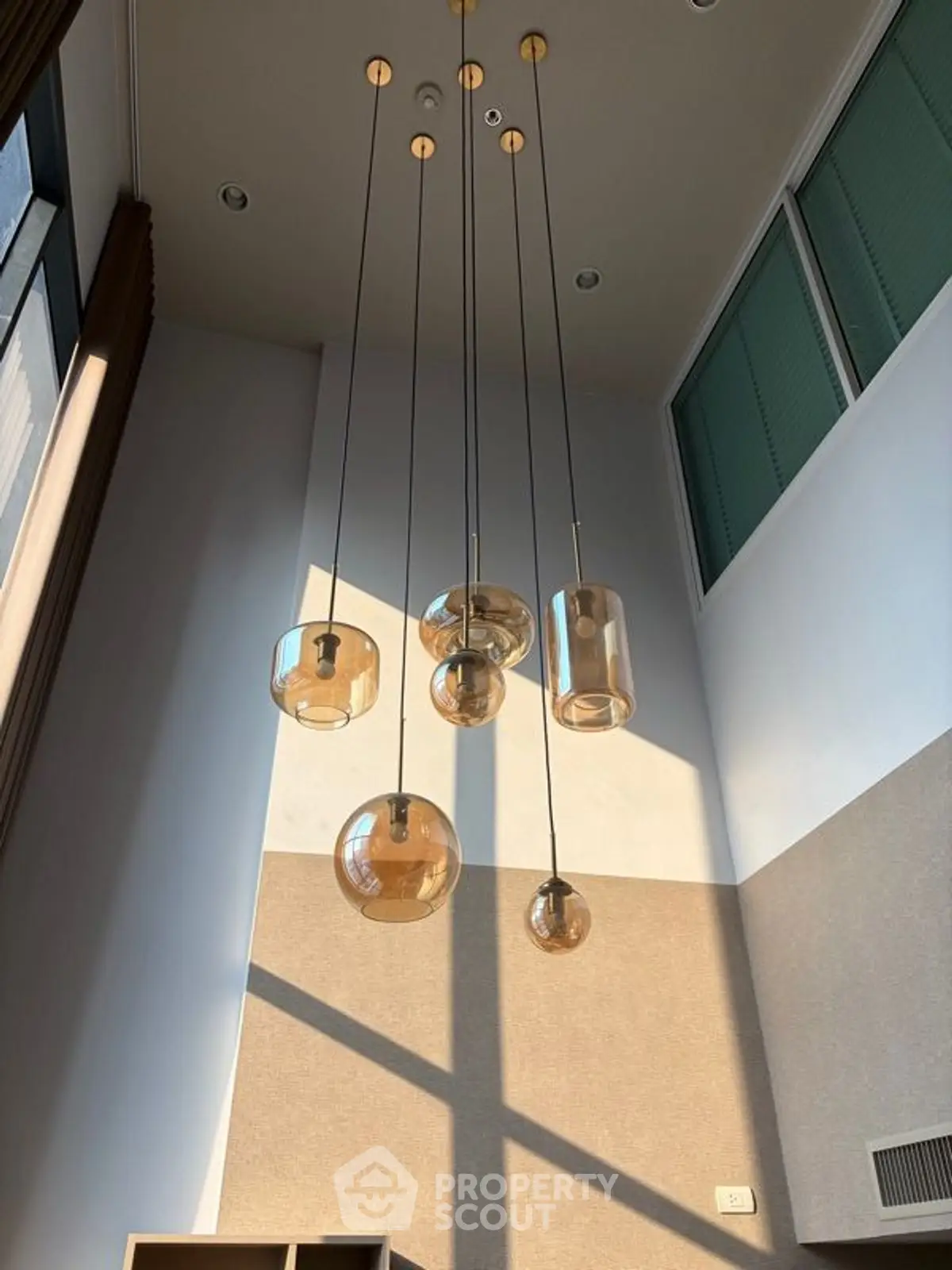 Modern high ceiling living room with elegant pendant lights and large windows